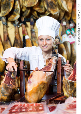 Woman in uniform slicing delicious prosciutto meat 39576088