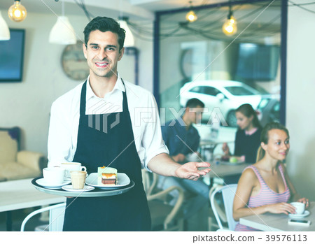 Waiter holding served tray meeting visitors at pastry bar Waiter holding served tray meeting visitors at pastry bar 39576113