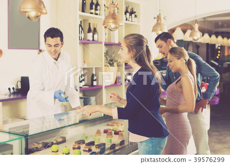 Hospitable man confectioner serving visitors 39576299
