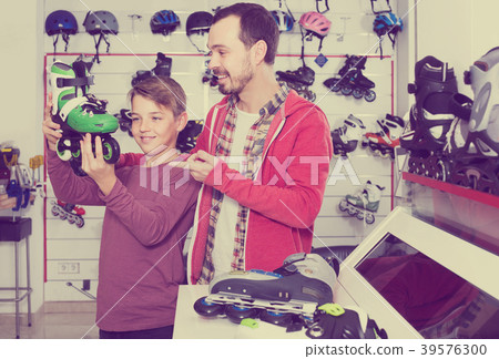 father and son deciding on new roller-skates in sports store father and son deciding on new roller-skates in sports store 39576300