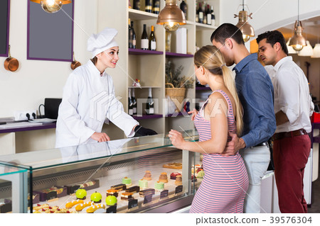 Pastry chef female is serving cakes from showcase Pastry chef female is serving cakes from showcase 39576304