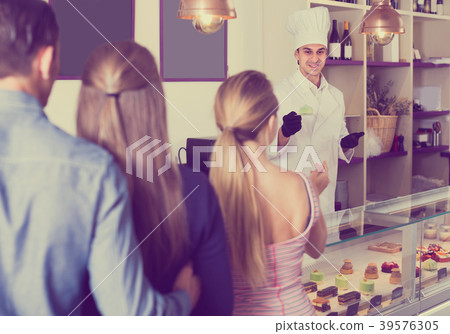 Man is offering delicious cakes from showcase Man is offering delicious cakes from showcase 39576305