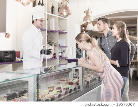 Positive pastry chef male is serving visitors 39576307