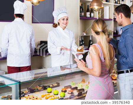 Female pastry chef helping customers to choose pasrties Female pastry chef helping customers to choose pasrties 39576340
