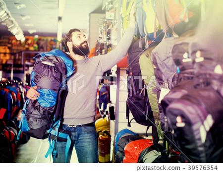 Male choosing new backpack in sports equipment shop Male choosing new backpack in sports equipment shop 39576354