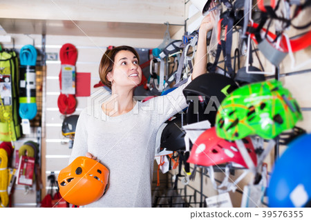 Woman choosing helmet in store Woman choosing helmet in store 39576355