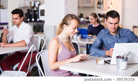 woman with boyfriend busying with device in modern cafe woman with boyfriend busying with device in modern cafe 39576359