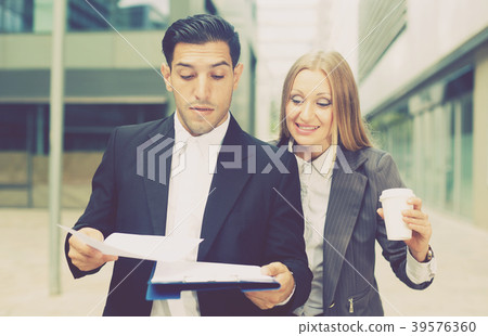 Businesswoman with her employee are drinking coffee and reading documents Businesswoman with her employee are drinking coffee and reading documents 39576360