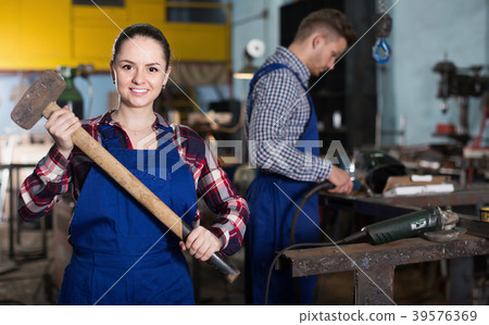 Young woman master is standing with sledgehammer Young woman master is standing with sledgehammer 39576369