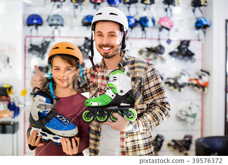 Father and son showing roller-skates they bought in sports store 39576372