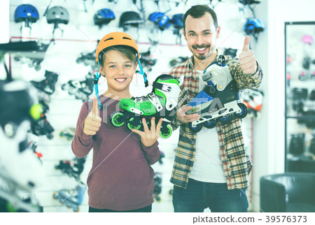 Father and son showing roller-skates they bought in sports store Father and son showing roller-skates they bought in sports store 39576373