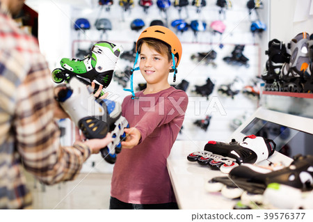 Male shop assistant helping boy to choose roller-skates in sports store Male shop assistant helping boy to choose roller-skates in sports store 39576377