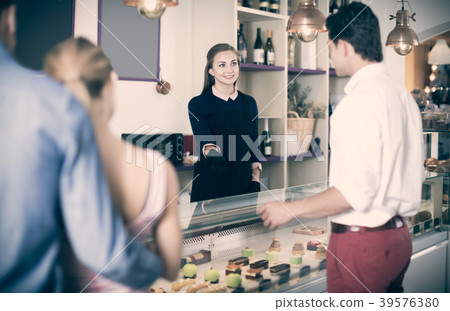 Adult female helping customers to choose sweets 39576380