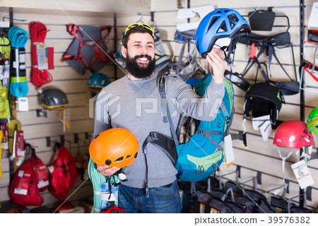 male customer examining helmets in sports equipment store male customer examining helmets in sports equipment store 39576382
