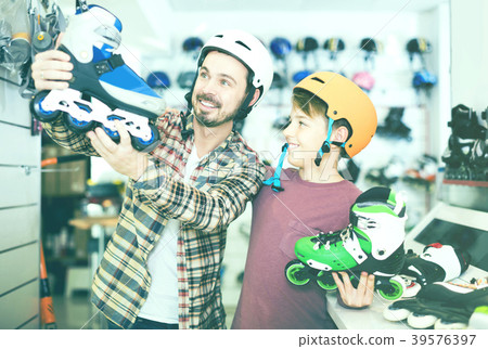 father and son deciding on new roller-skates in sports store 39576397