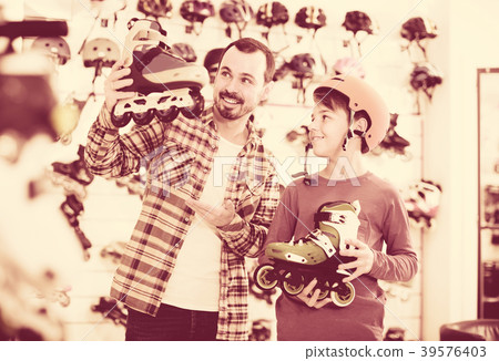 Male shop assistant helping boy to choose roller-skates in sports store Male shop assistant helping boy to choose roller-skates in sports store 39576403