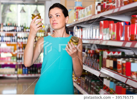 Smiling girl is holding jar of preserved olives Smiling girl is holding jar of preserved olives 39576575