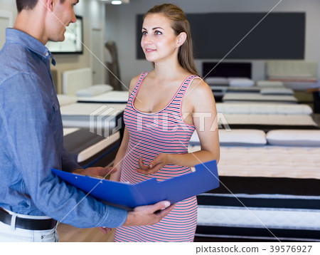 Laughing salesman demonstrating to girl mattress 39576927