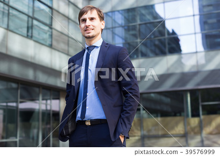 Smiling businessman standing outdoors Smiling businessman standing outdoors 39576999