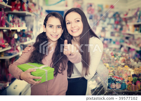 Woman and smiling daughter with gifts standing in the toys shop 39577102