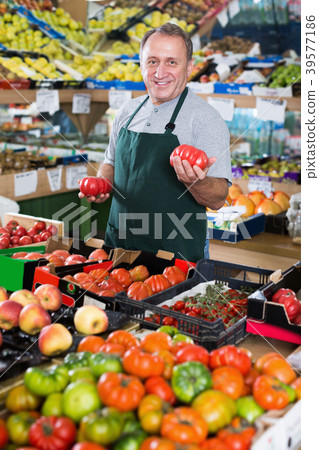 Smiling male seller is standing with box with tomatos Smiling male seller is standing with box with tomatos 39577186