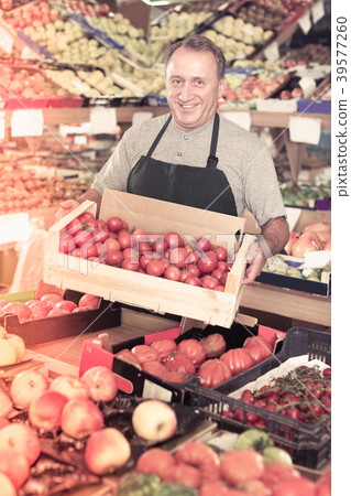 Man seller demonstraiting red tomatos Man seller demonstraiting red tomatos 39577260