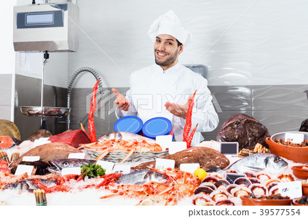 Handsome male chef standing behind icy showcase of fish restaurant, offering fresh seafood Handsome male chef standing behind icy showcase of fish restaurant, offering fresh seafood 39577554
