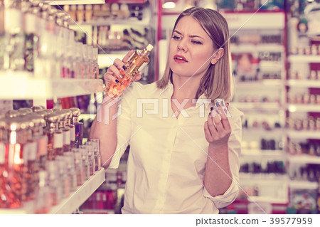 Girl with displeasure sniffing unpleasant smell of perfume Girl with displeasure sniffing unpleasant smell of perfume 39577959
