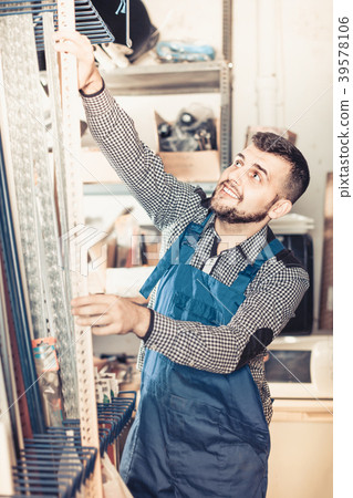 Young man worker examining plastic corners for tiles and floors 39578106