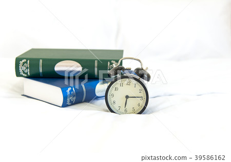 Alarm clock with book on bed in morning  39586162