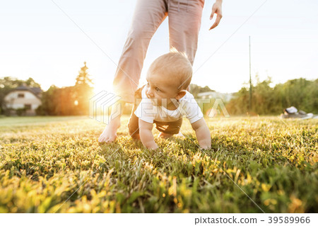 Baby boy with unrecognizable mother crawling 39589966