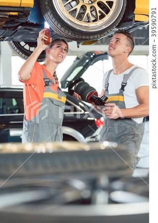 Experienced female auto mechanic with colleague at Experienced female auto mechanic with colleague at 39590791