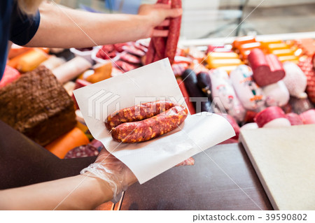 Sales woman in butchery holding sausage wrapped in Sales woman in butchery holding sausage wrapped in 39590802