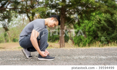 Men knelt down to do up his shoelaces 39594499