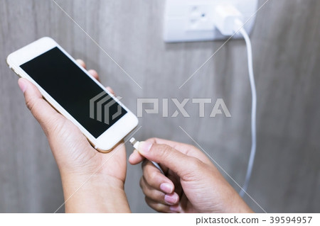 Power plug charging phone in room. 39594957