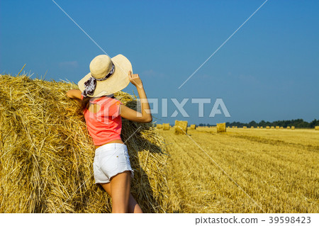 Young brunette country girl in hat near haystacks 39598423
