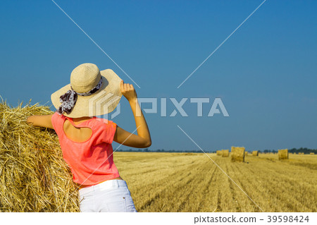 girl is standing near a straw bale on the field girl is standing near a straw bale on the field 39598424