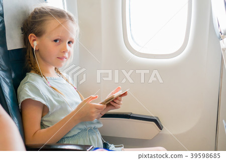 Adorable little girl traveling by an airplane Adorable little girl traveling by an airplane 39598685
