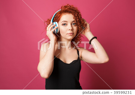 curly redhead girl listens  music with headphones 39599231