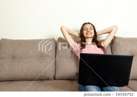 Relaxed woman lying on sofa with laptop on pillow Relaxed woman lying on sofa with laptop on pillow 39599792