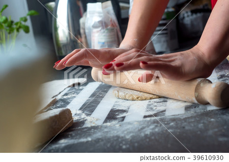 Woman rolling dough for pasta at the kitchen table 39610930