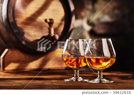 Two glass of Cognac and old oak barrel defocussed Two glass of Cognac and old oak barrel defocussed 39612638