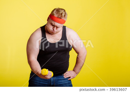 Fat man try to lift small yellow dambbell 39613607