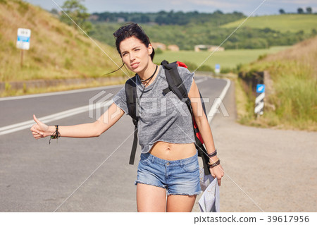 women with paper map waving at car on a concrete road in the cou 39617956