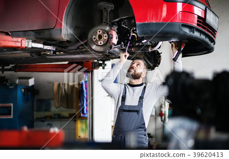 Man mechanic repairing a car in a garage. Man mechanic repairing a car in a garage. 39620413
