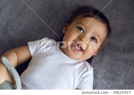 very cheerful baby boy in white clothes lying on 39624457
