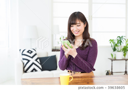 看智能手機的婦女在屋子裡 看智能手機的婦女在屋子裡 39638605