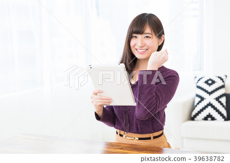 觀看一種片劑的婦女在屋子裡 觀看一種片劑的婦女在屋子裡 39638782
