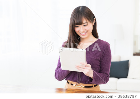 觀看一種片劑的婦女在屋子裡 觀看一種片劑的婦女在屋子裡 39638787