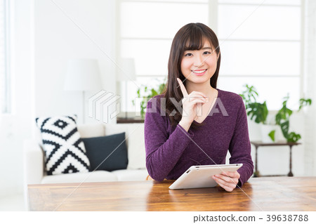 觀看一種片劑的婦女在屋子裡 觀看一種片劑的婦女在屋子裡 39638788